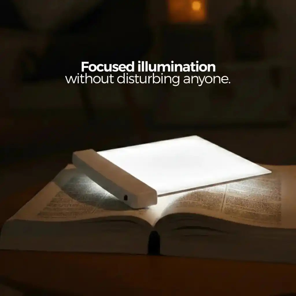 VisionGlow white flat panel on open book with focused bright illumination on wooden surface in dark room — reads without disturbing anyone