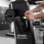 Person at a gym machine with the Tazzi IronGrip Gym Vault bag placed nearby — lifestyle gym scene showing the bag in its natural environment alongside workout equipment